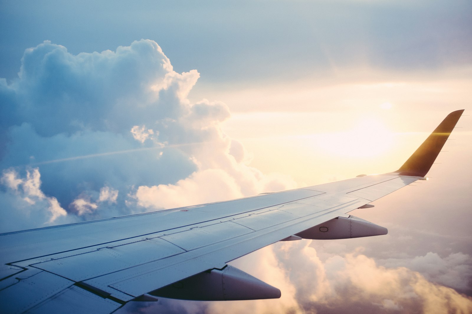 Aircraft wing above the clouds representing air, rail and maritime travel claims